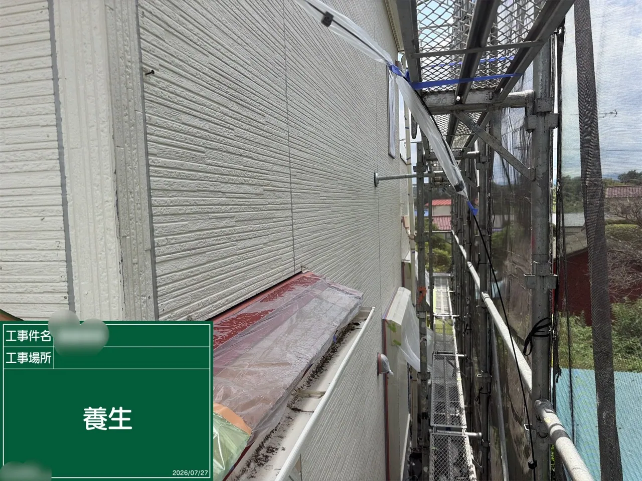 外壁と出窓まわりを養生した足場内の施工現場