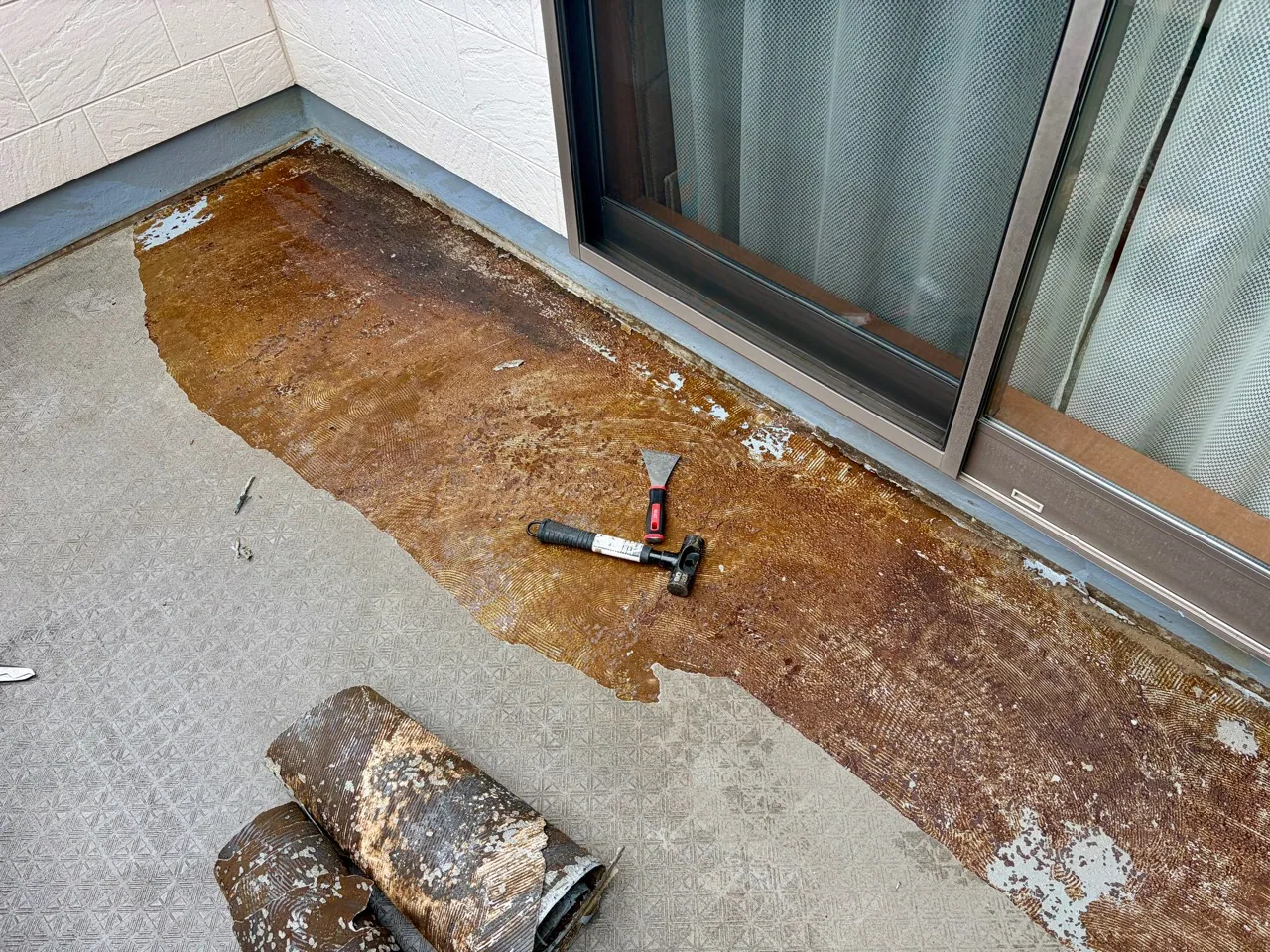 長尺シートを剥がしてのりを除去しているベランダ床
