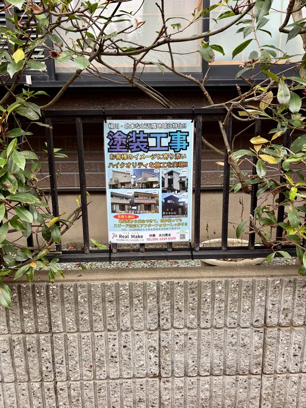 フェンスに掲示されたReal Makeの塗装工事ポスター